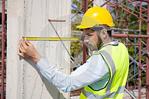 Engineer young man using tape measure for check and examining length of structure with professional at construction site.