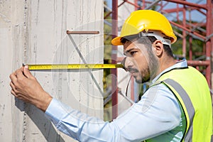 Engineer young man using tape measure for check and examining length of structure with professional at construction site.