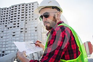 Engineering Consulting People on construction site holding blueprint in his hand. Building inspector