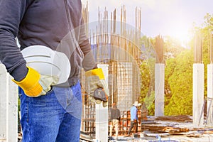 Engineering hand holding white safety hat interior working construction site in building