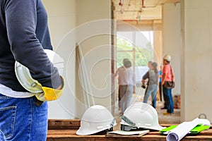 Engineering hand holding white safety hat interior working construction site in building with copy space