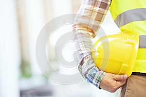 Engineering male construction worker stand holding safety yellow helmet and wear reflective clothing