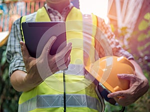 Engineering man standing with yellow safety helmet and holding tablet, work concept