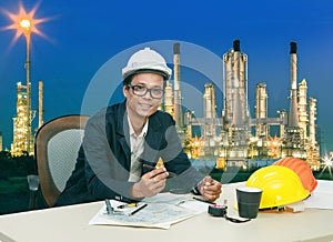 Engineering man working on table against beautiful lighting of oil refinery plant