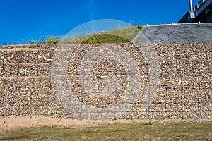 Engineering structure made of stones behind metal wire netting to strengthen the river bank near the road bridge