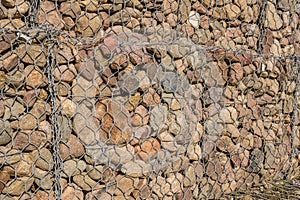 engineering structure made of stones behind metal wire netting to strengthen the river bank near the road bridge