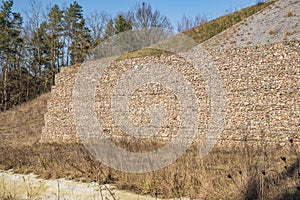 engineering structure made of stones behind metal wire netting to strengthen the river bank near the road bridge