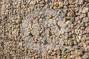 engineering structure made of stones behind metal wire netting to strengthen the river bank near the road bridge