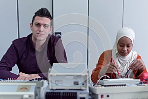 Engineering students working in the lab. Students are adjusting an electrical`s components inside lab