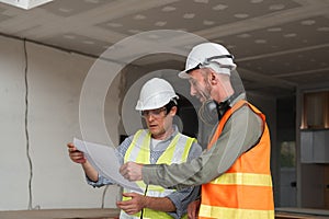 Engineering Team Planning Construction Work with Blueprints and Safety Gear in Modern Building Site