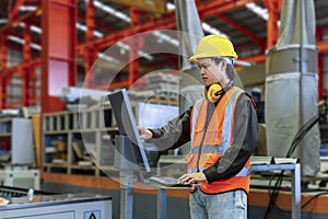 Engineering technician worker is operating the machine inside factory using touch screen computer monitor to command the order for