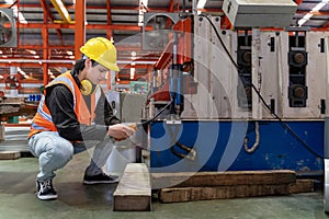 Engineering technician worker is operating the machine inside factory using touch screen computer monitor to command the order for