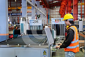 Engineering technician worker is operating the machine inside factory using touch screen computer monitor to command the order for