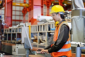 Engineering technician worker is operating the machine inside factory using touch screen computer monitor to command the order for