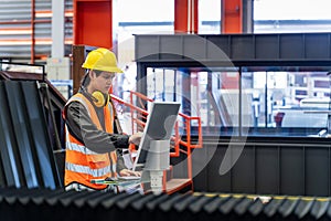 Engineering technician worker is operating the machine inside factory using touch screen computer monitor to command the order for