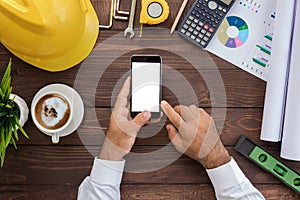 Engineering using phone on his workspace top view