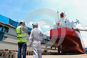 Engineering Workers planning hand holding blue print of the commercial ship standing on floating dry dock yard