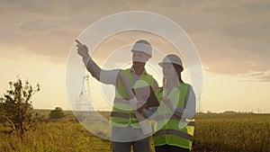 Engineering working on High-voltage tower, Check the information on the tablet computer two employees man and woman.