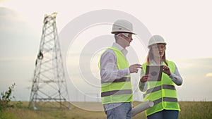 Engineering working on High-voltage tower, Check the information on the tablet computer two employees man and woman.