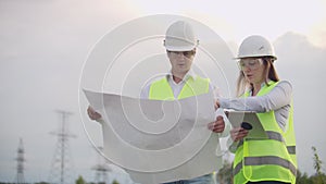 Engineering working on High-voltage tower, Check the information on the tablet computer two employees man and woman.