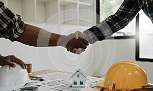 Engineers or architecture shaking hands at construction site for architectural project, holding safety helmet on their