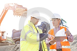 Engineers discussing over documents at construction site