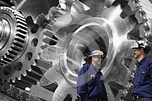 Engineers examining large gears and cog machinery