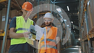 Engineers in a factory warehouse. Two workers in a warehouse are discussing work.