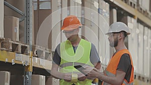 Engineers in a factory warehouse. Two workers in a warehouse are discussing work.