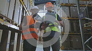 Engineers in a factory warehouse. Two workers in a warehouse are discussing work.