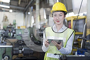 Engineers female and skilled technicians are maintaining machinery. Professional technicians are holding a tablet to control work