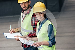 engineers in hardhats working with blueprint and clipboard