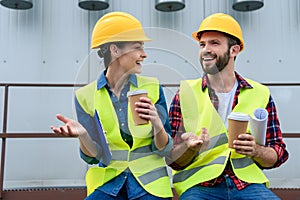 engineers in helmets with blueprint on coffee break sitting