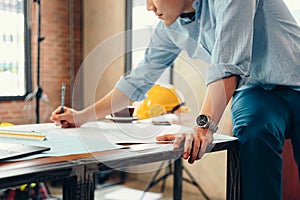 Engineers holding a pen pointing to a building and  drawing outlay construction plan as guide for builders with details. Engineer