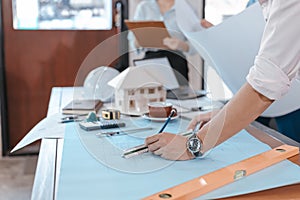 Engineers holding a pen pointing to a building and  drawing outlay construction plan as guide for builders with details. Engineer