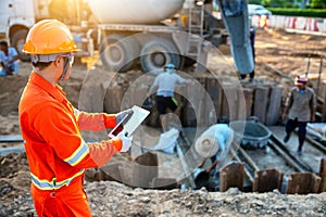 Engineers inspect the pouring of concrete with tablet