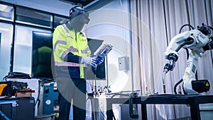 Engineers mechanic using computer controller Robotic arm for welding steel in steel factory workshop. Industry robot programming