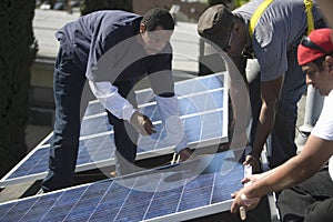 Engineers Placing Solar Panel Together On Rooftop