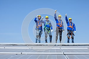 Engineers raised their fist up on solar panels against blue sky after finish their work