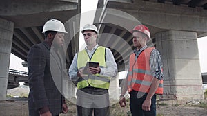 Engineers standing with bearded boss in white hard hat
