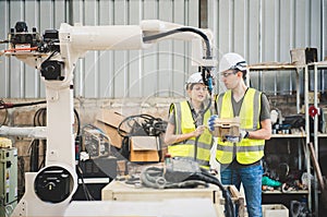Engineers team mechanic using computer controller Robotic arm for welding steel in steel factory workshop. Industry robot