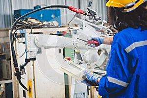 Engineers team mechanic using computer controller Robotic arm for welding steel in steel factory workshop. Industry robot
