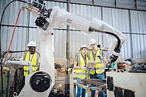 Engineers team mechanic using computer controller Robotic arm for welding steel in steel factory workshop. Industry robot