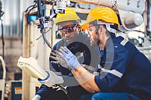 Engineers team mechanic using computer controller Robotic arm for welding steel in steel factory workshop. Industry robot
