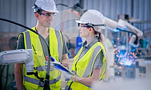 Engineers team mechanic using computer controller Robotic arm for welding steel in steel factory workshop. Industry robot