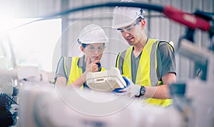 Engineers team mechanic using computer controller Robotic arm for welding steel in steel factory workshop. Industry robot