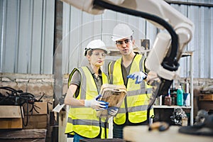 Engineers team mechanic using computer controller Robotic arm for welding steel in steel factory workshop. Industry robot