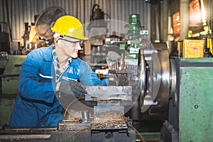 technicians man are working by controlling steel lathes, in parts production line at workplace