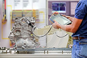 Engineers use a wireless remote for control robotic for work scanning part of automobile via conveyor belt