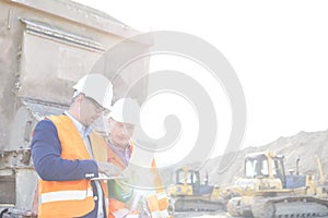 Engineers using laptop at construction site against clear sky